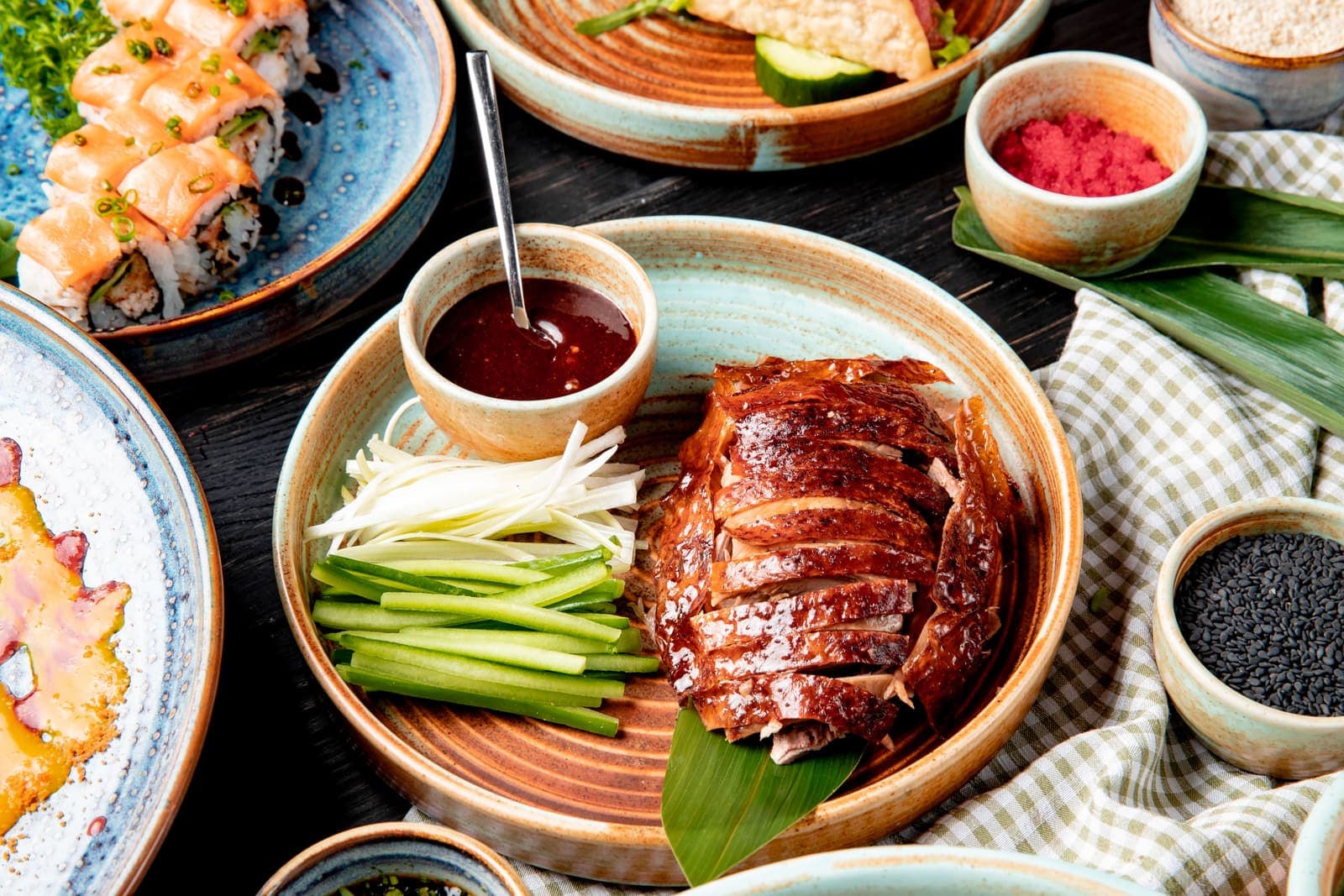 A whole Peking duck on the carving board, lacquered skin sliced and laid beside pancakes, scallion and sweet bean sauce