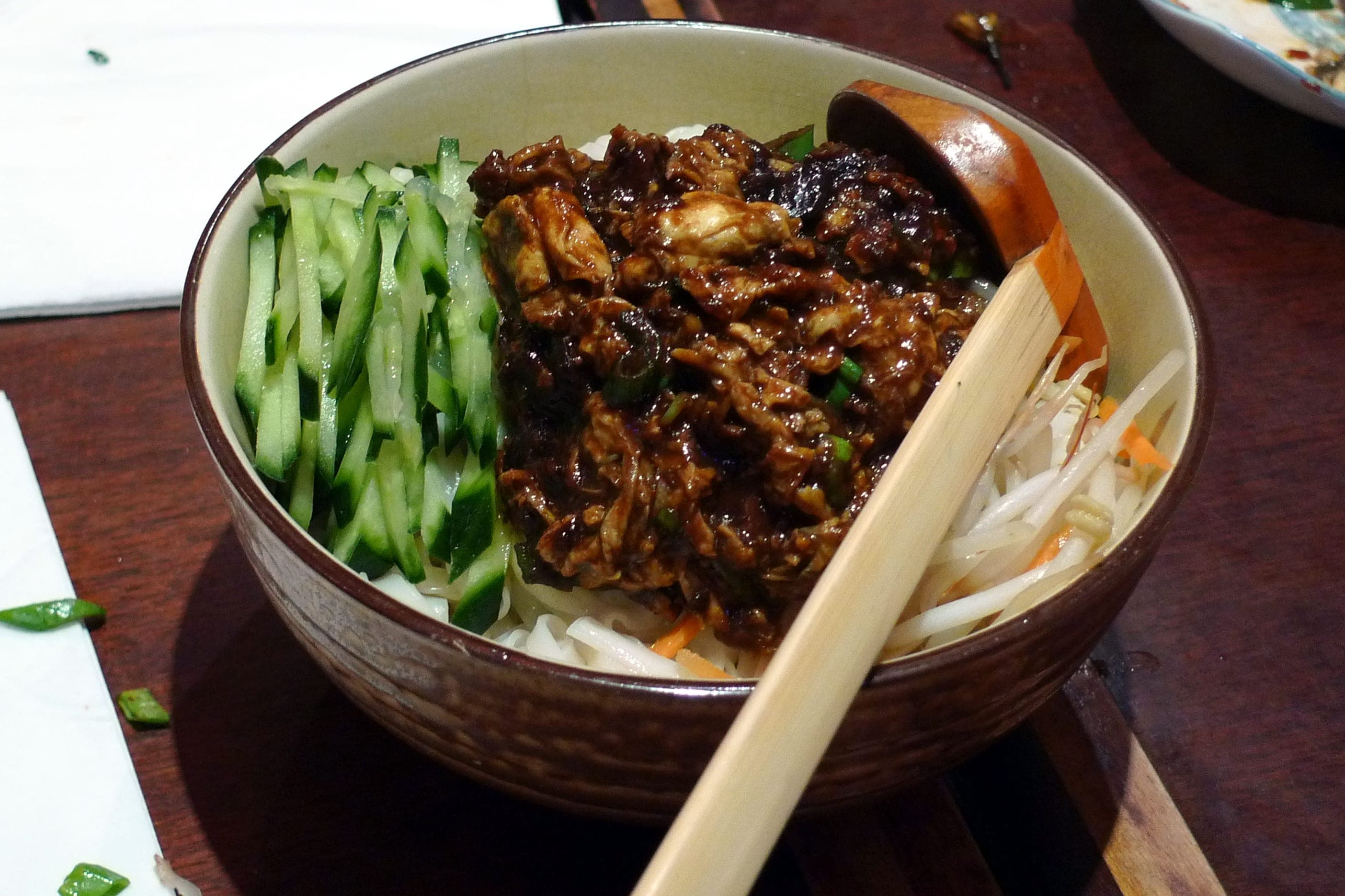 A bowl of Beijing zhajiangmian, wheat noodles topped with fermented soybean paste, cucumber and bean sprouts