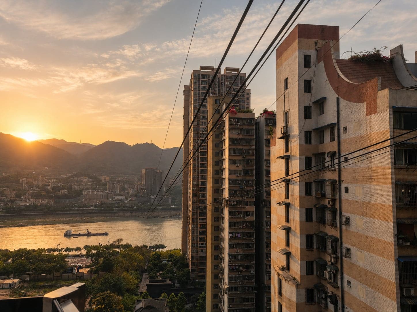 The Yangtze Cableway's wires stretching across the river at golden hour, Yuzhong towers in the foreground and the south-bank ridge in haze beyond