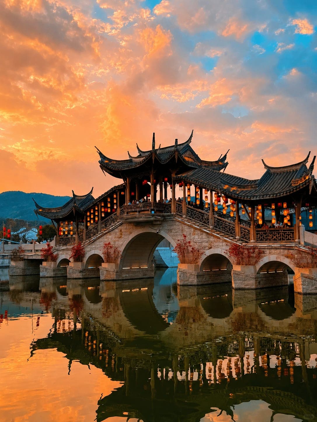 A Min-style covered stone bridge over a lantern-lit canal at sunset, Minyue Water Town, Fuzhou