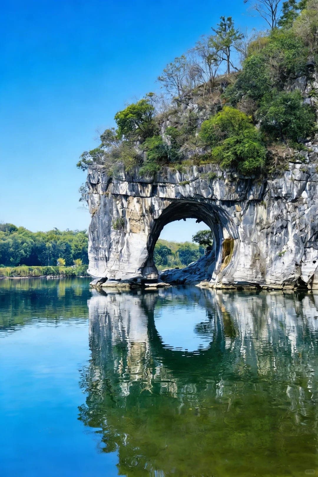 Elephant Trunk Hill on the Li River, the karst formation shaped like an elephant lowering its trunk to drink, with Water Moon Cave forming a perfect circle with its reflection on the still water