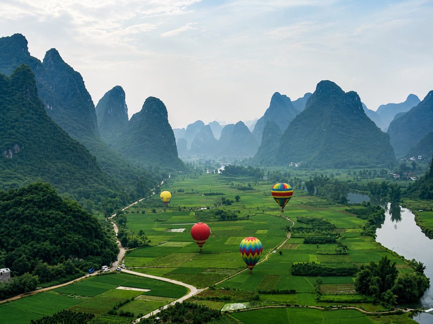 A hot air balloon rising over the Yangshuo karst peaks at sunrise