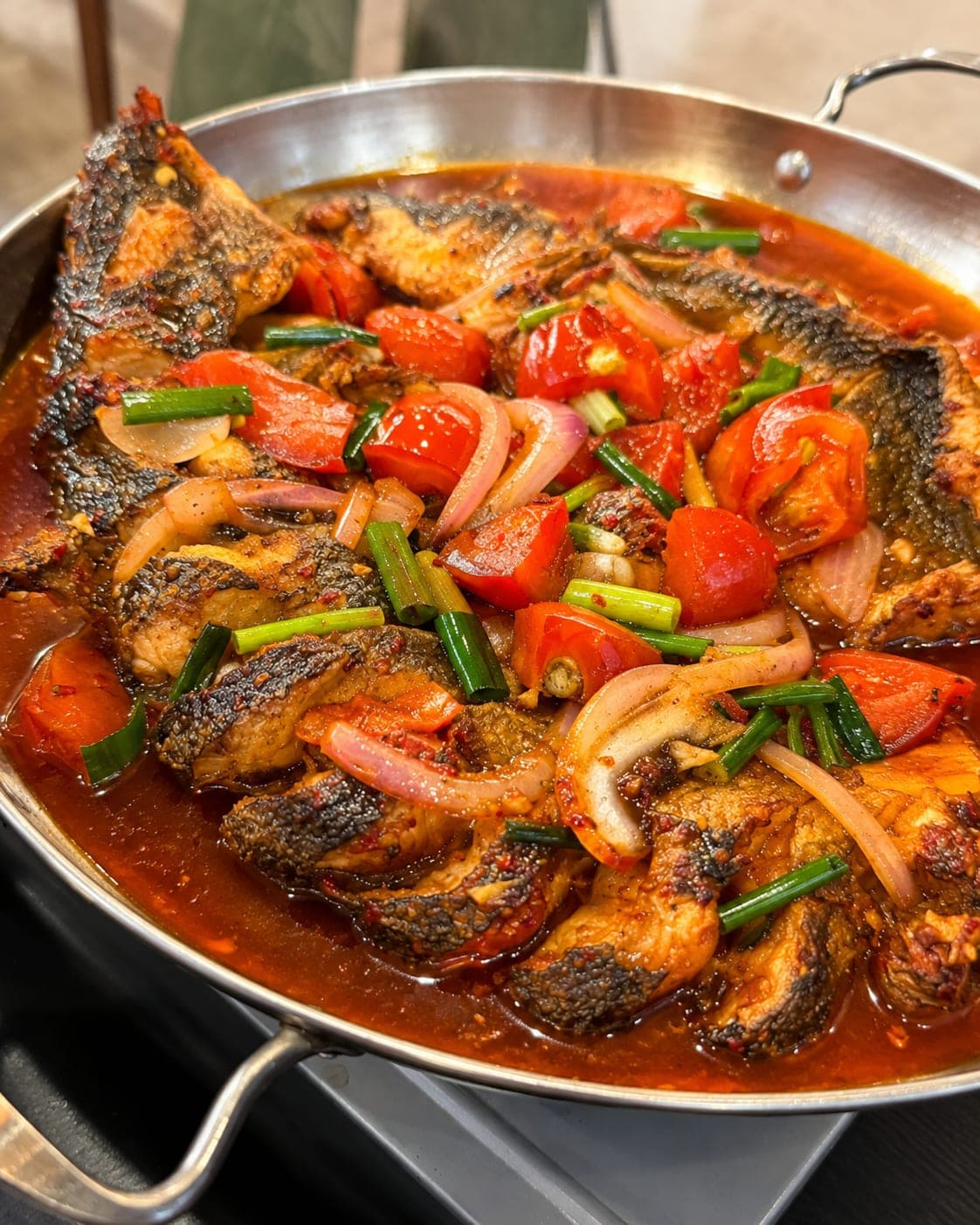 A whole carp braised with beer, tomato and scallion on a metal plate, Yangshuo style