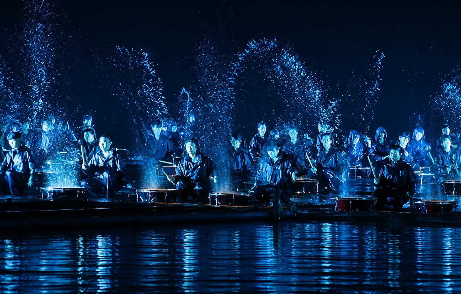 Impression West Lake performance: a solo dancer crossing the submerged lake stage with the southern hills lit blue behind, Hangzhou