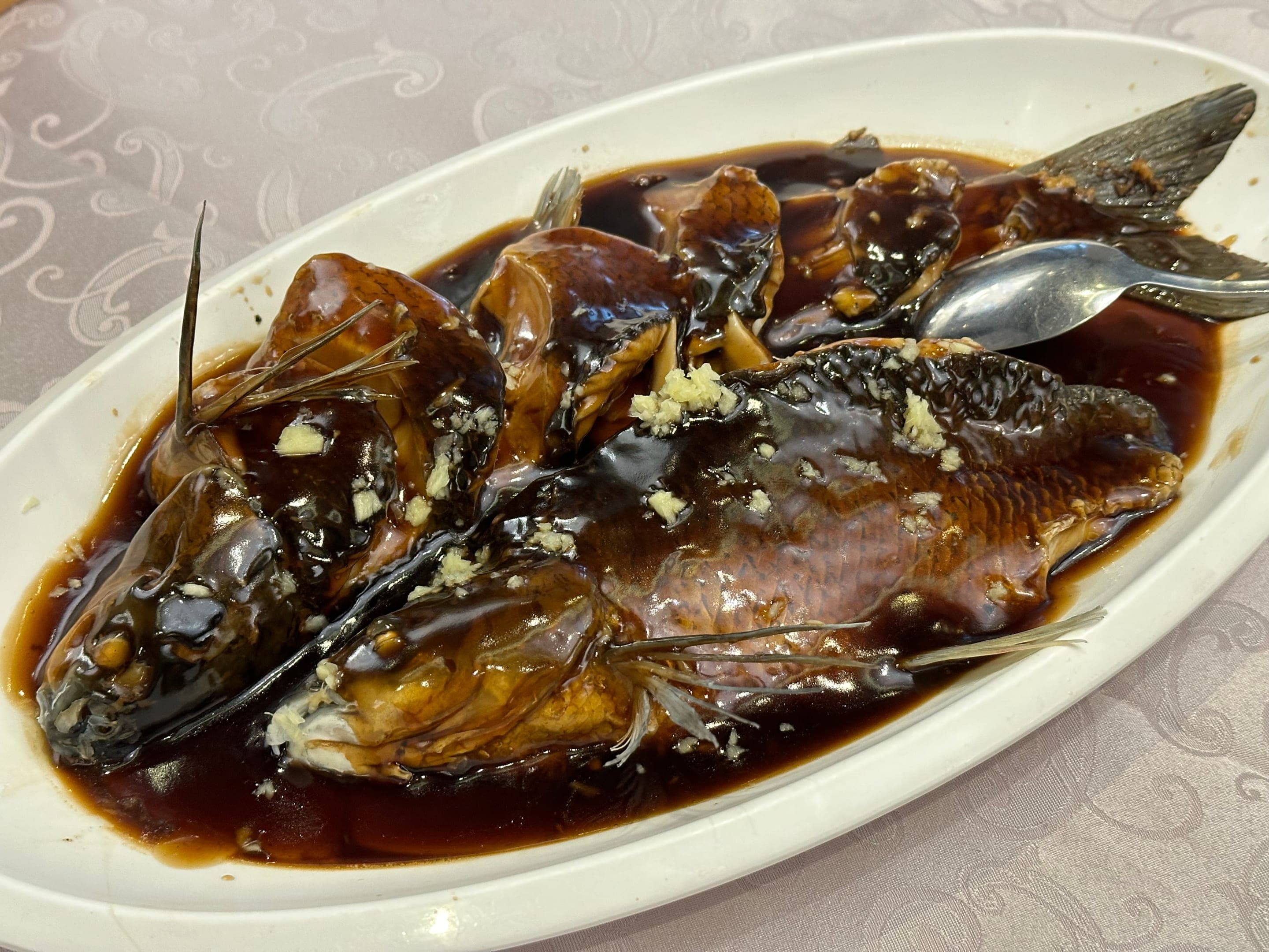 West Lake fish in vinegar at a Hangzhou table, whole grass carp under a bright sweet-and-sour glaze with ginger and Zhenjiang vinegar