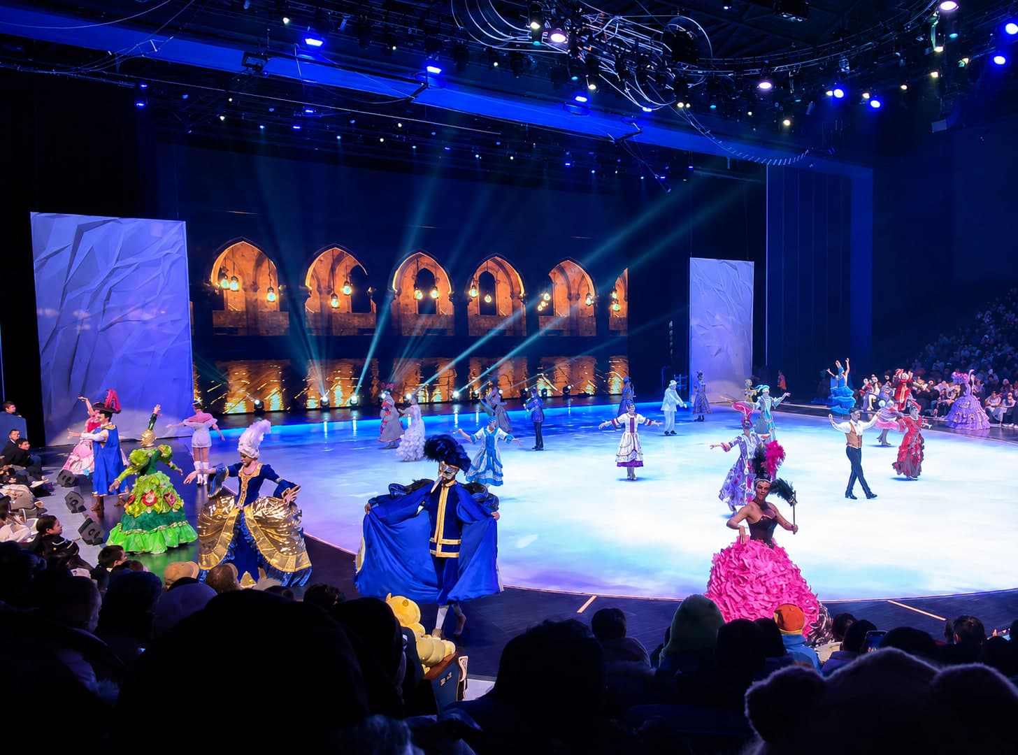 The Habin Show arena at the heart of the Harbin Ice and Snow World grounds, the circular frozen rink and surrounding ice pavilions lit in coloured stage light at night