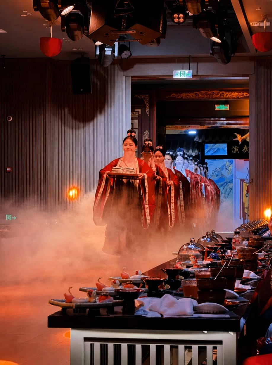 The Red Gate Banquet in Harbin: a turn-of-the-century Russian-Manchurian dining room set for the dinner-and-stage evening, with live ensemble moving between courses