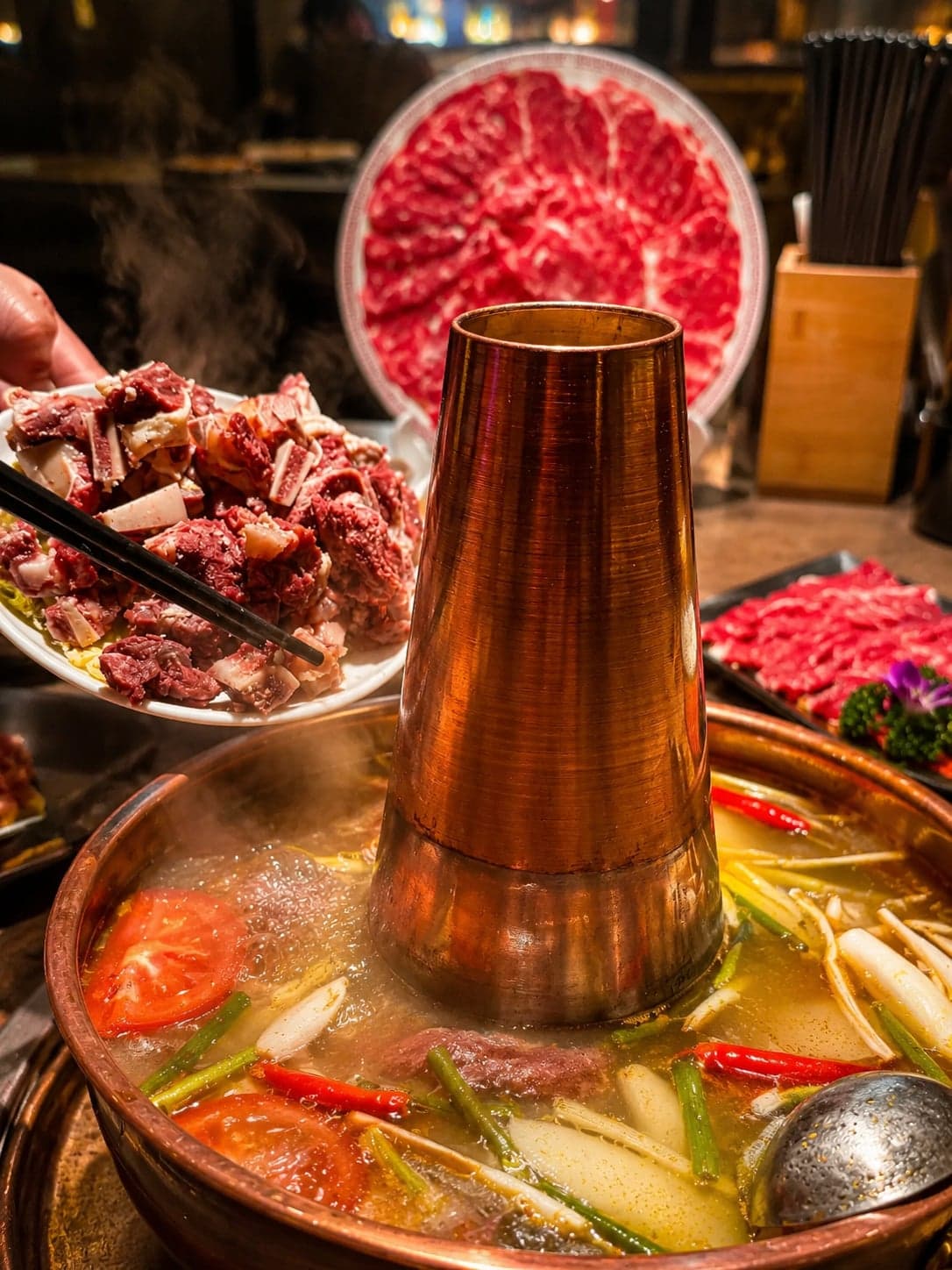 A copper hotpot at Sangjila Lhasa, hand-sliced yak shoulder and yak-milk yoghurt dumplings around the central pot