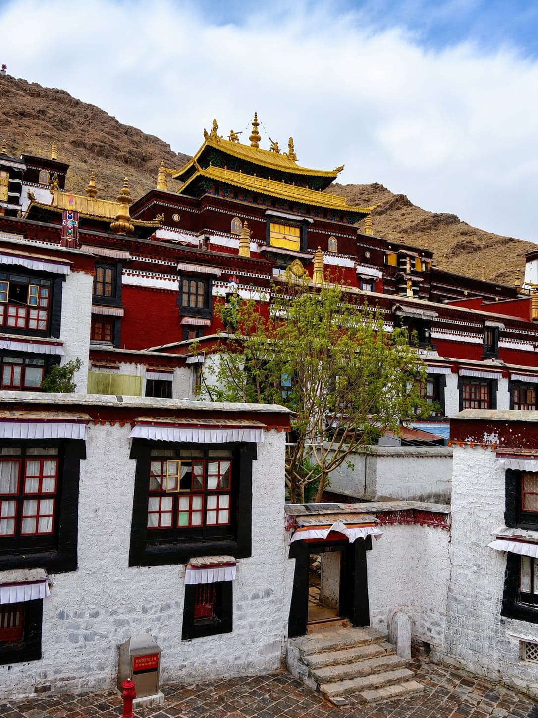 The gold-roofed chapels and white-walled assembly halls of Tashilhunpo Monastery climbing the hillside above Shigatse