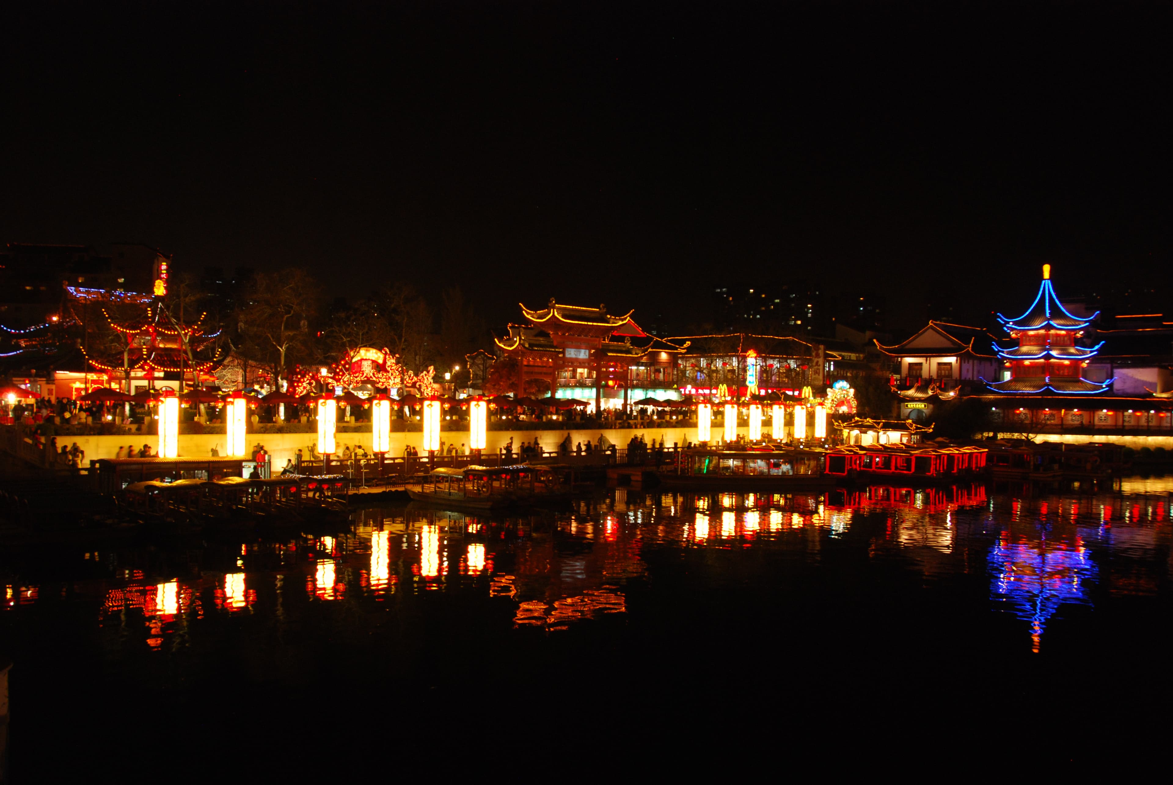 夜色中的秦淮内河之上一艘红漆画舫，两岸夫子庙与红灯笼绵延