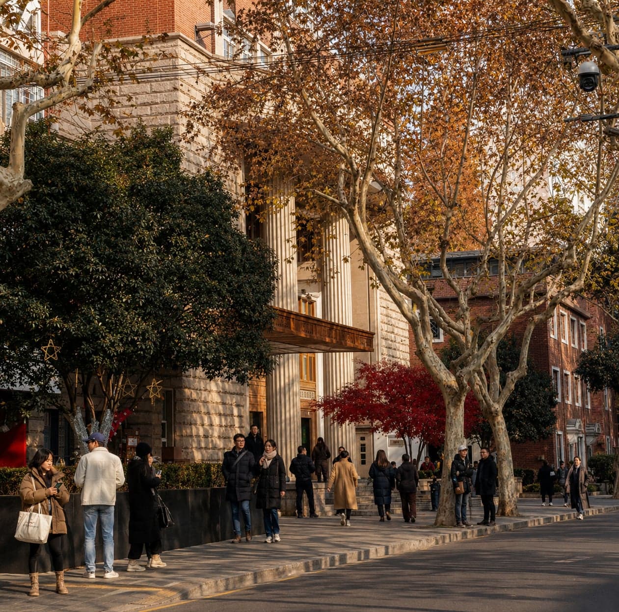 Anfu Road in Shanghai's former French Concession, plane trees in autumn colour arching over the street and pedestrians passing a colonnaded 1920s apartment block in warm afternoon light