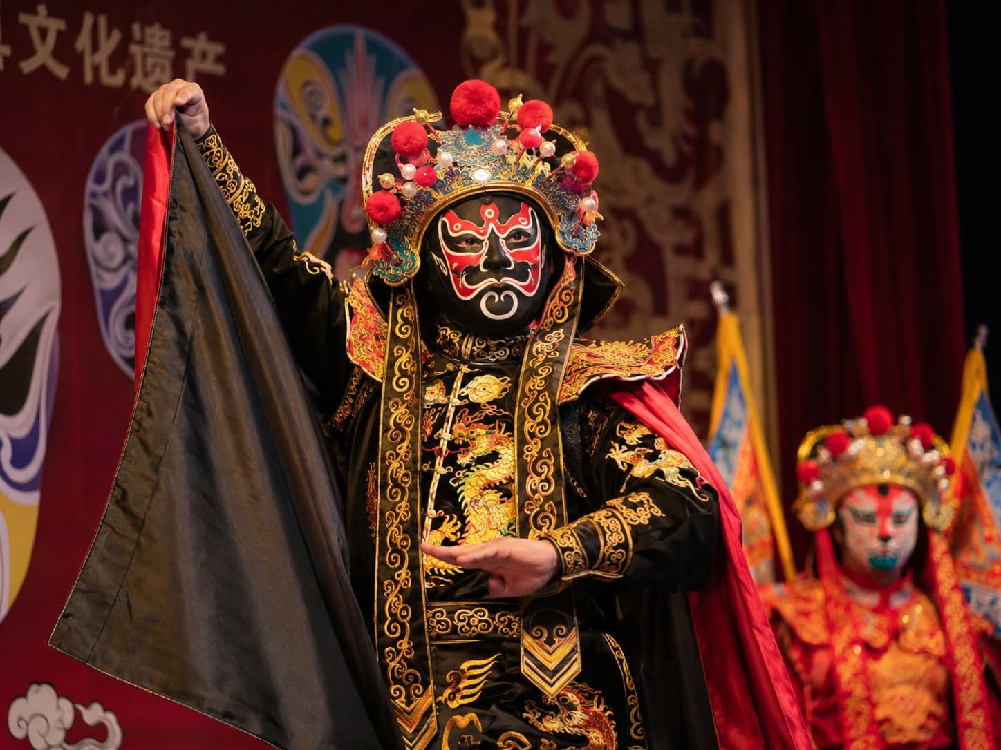 A Sichuan opera performer in dragon-embroidered robe and painted mask, mid-performance