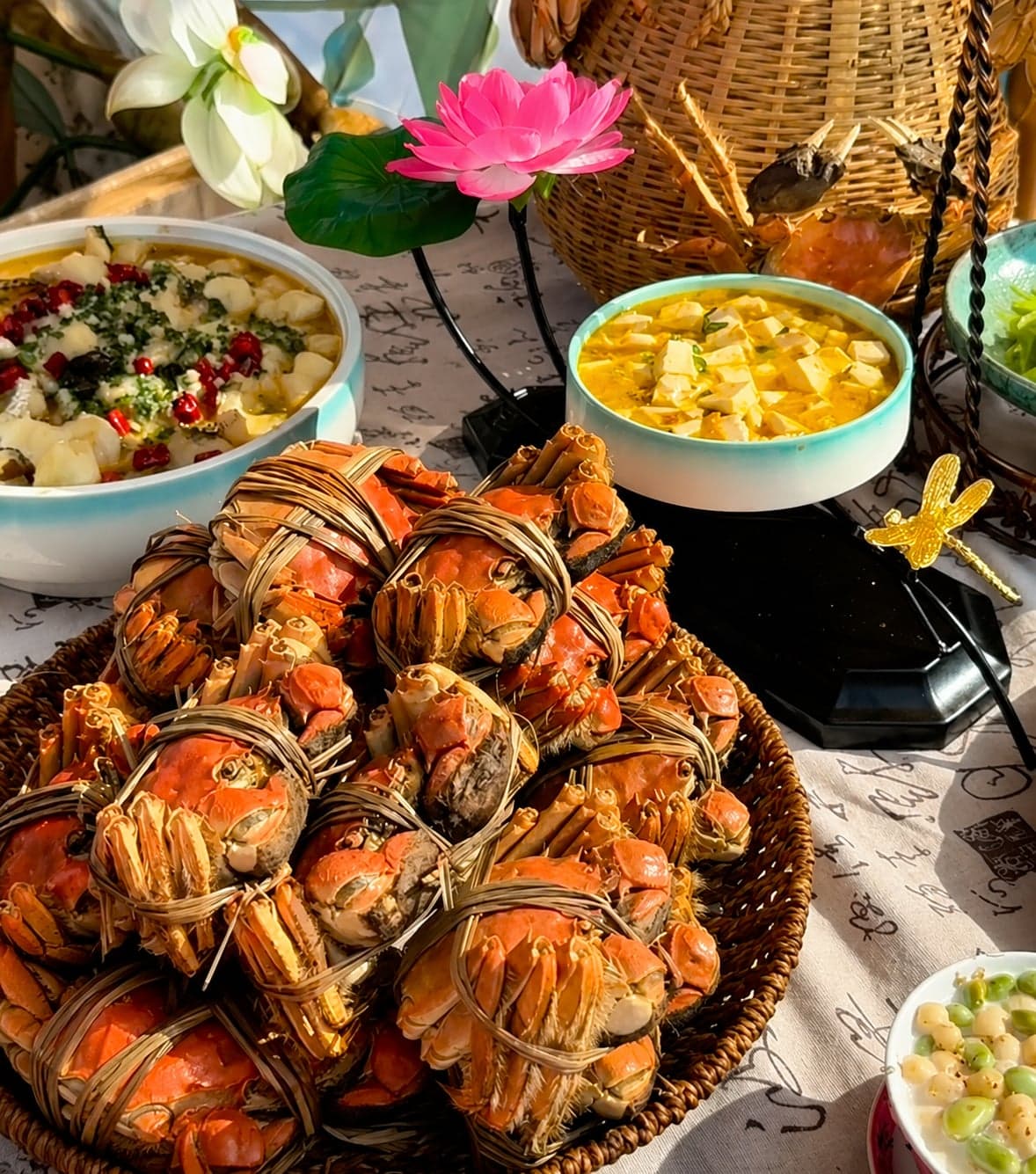 A basket of grass-tied Yangcheng Lake hairy crabs at the table, served with crab-roe tofu and lotus garnish