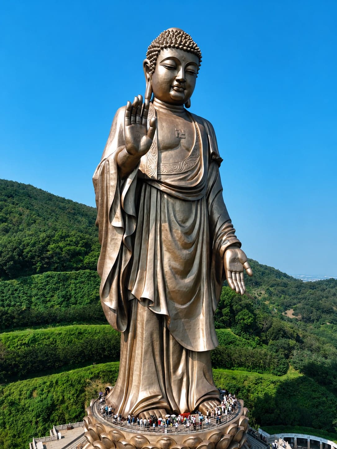 The 88-metre Lingshan Buddha at Wuxi, the bronze statue rising from its lotus platform with visitors on the viewing deck below and Lingshan's wooded hills behind