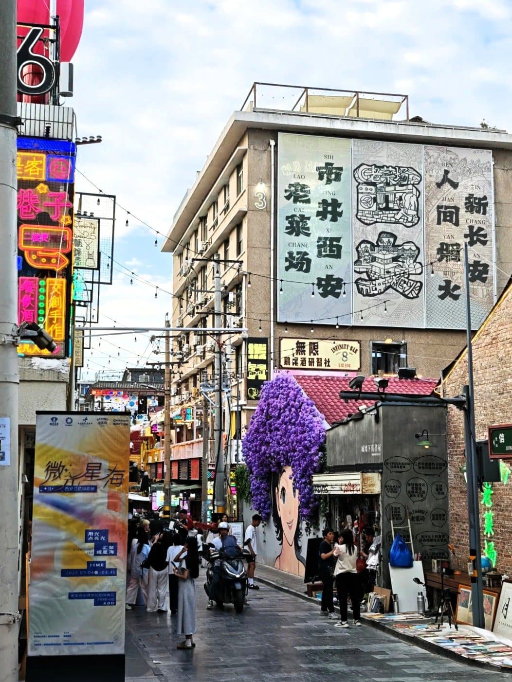 从街巷仰望老菜场：楼面大字招牌一字排开，『市井 · 老菜场 · 西安 · 新长安 · 人间烟火』错落其上，灯串、红灯笼与人潮在下方熙攘