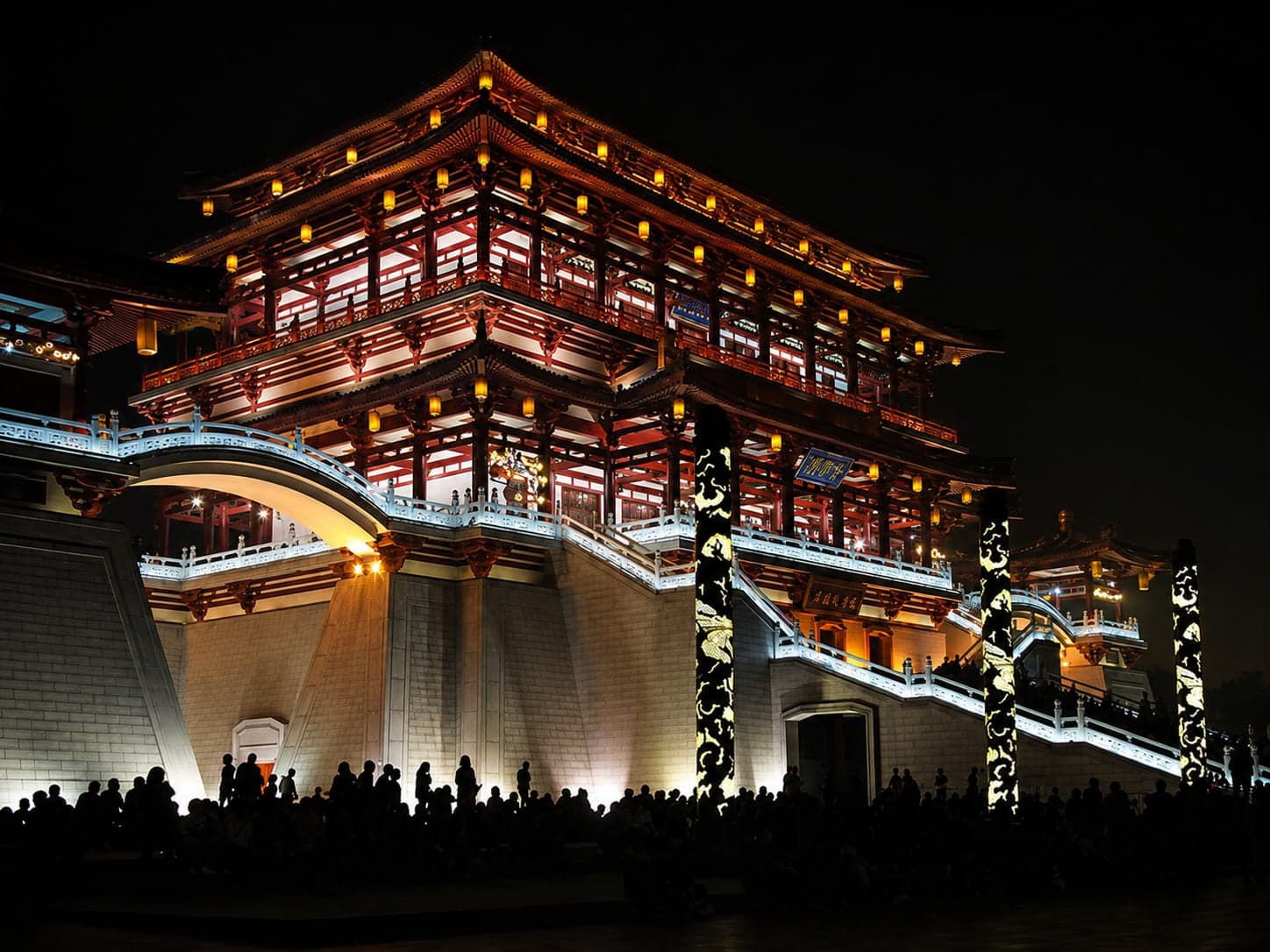 Tang-style pavilions on Furong Lake at sunset, lights beginning to show through the wooden eaves and reflected on the water, Tang Paradise, Xi'an