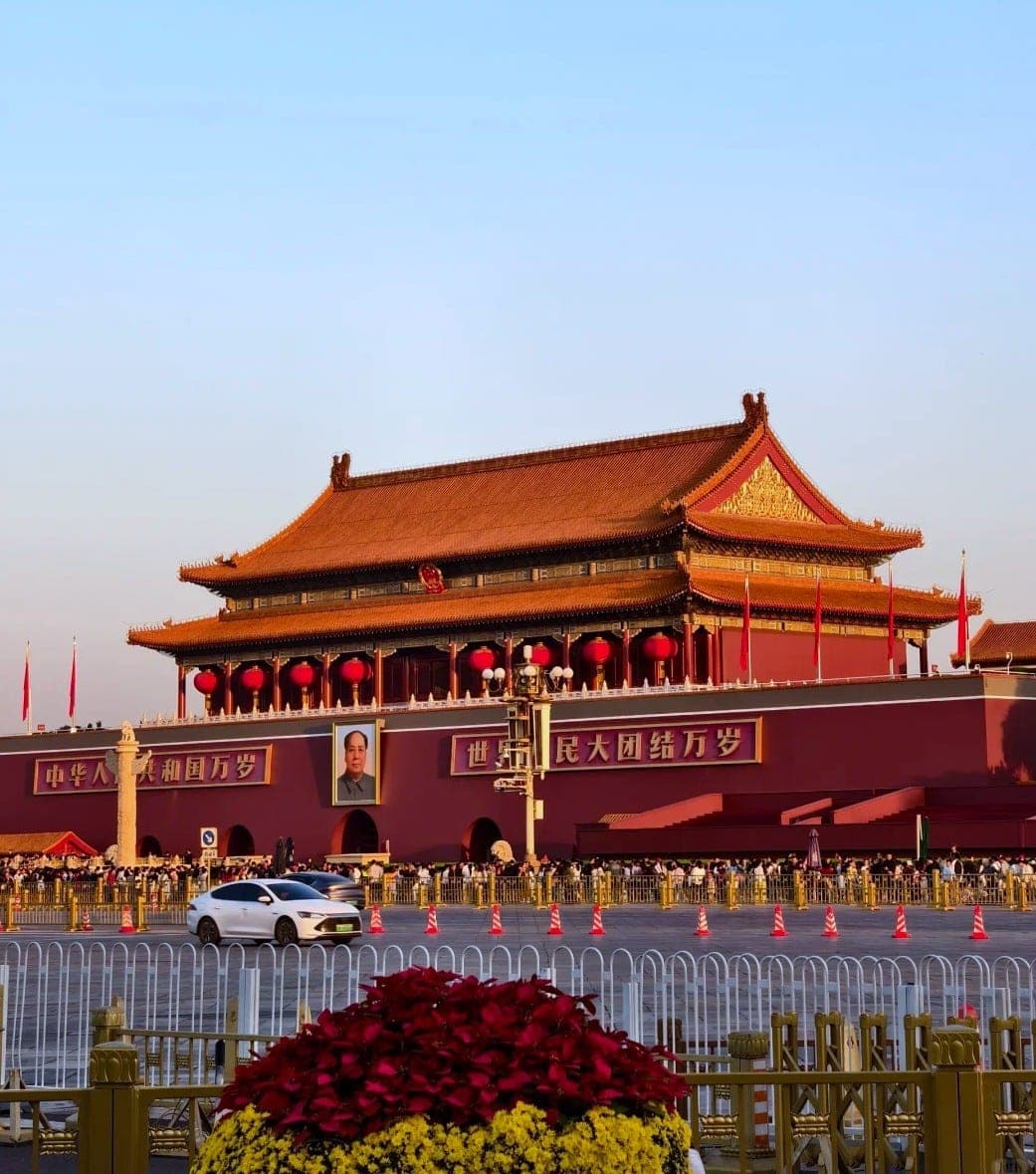 The Gate of Heavenly Peace at golden hour, red lanterns along its eaves and crowds gathered at the square's barriers