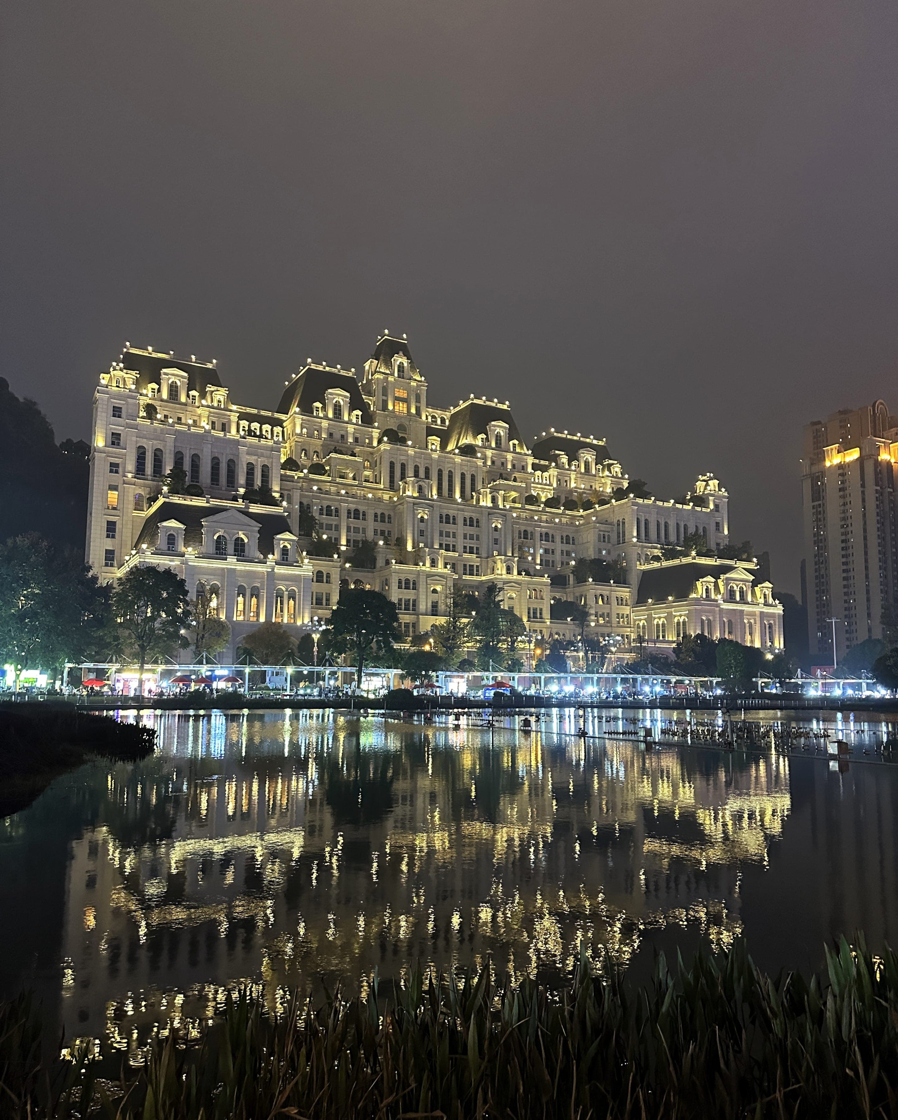 贵阳花果园新古典风地标,夜色之下白色立面灯火齐明,倒映于广场水面