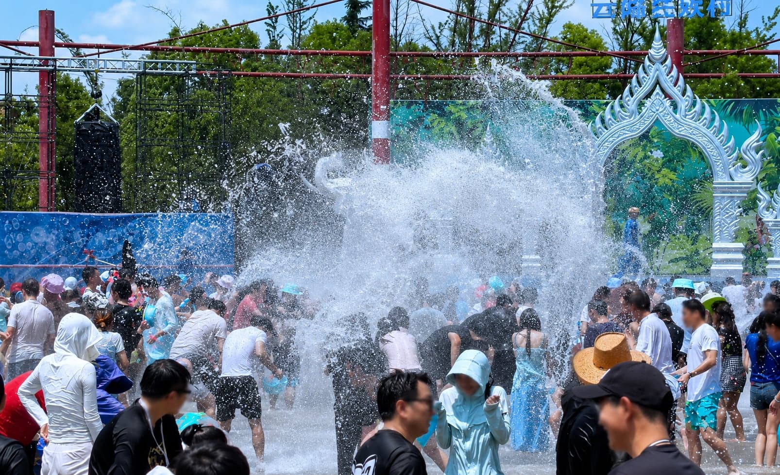Performers in ethnic dress ranged across the red-rock Impression Lijiang stage with snow peaks behind, placeholder for the Dai Water Splashing Festival at the Yunnan Ethnic Village