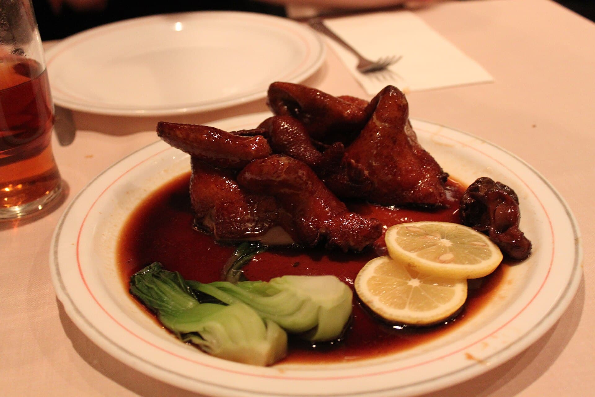 一只粤式烤乳鸽,琥珀色釉皮、内里鲜红,深圳宴席之上