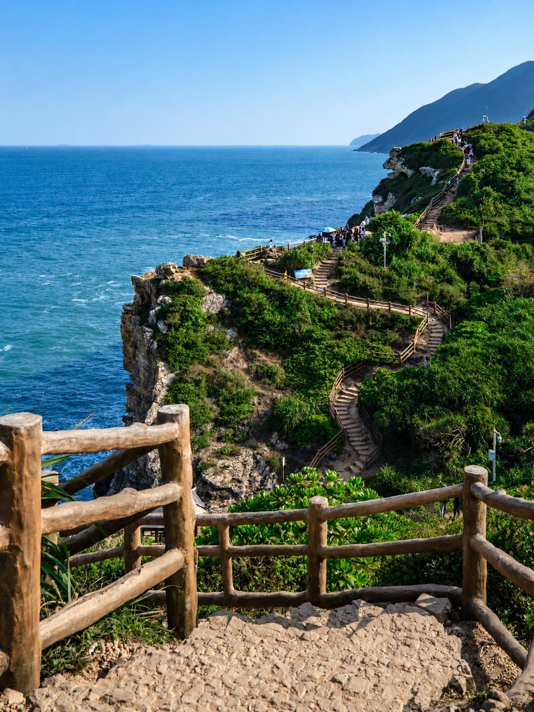 杨梅坑海湾清晨一景,青山自岸边接入海面,黑色礁石沿岸延伸