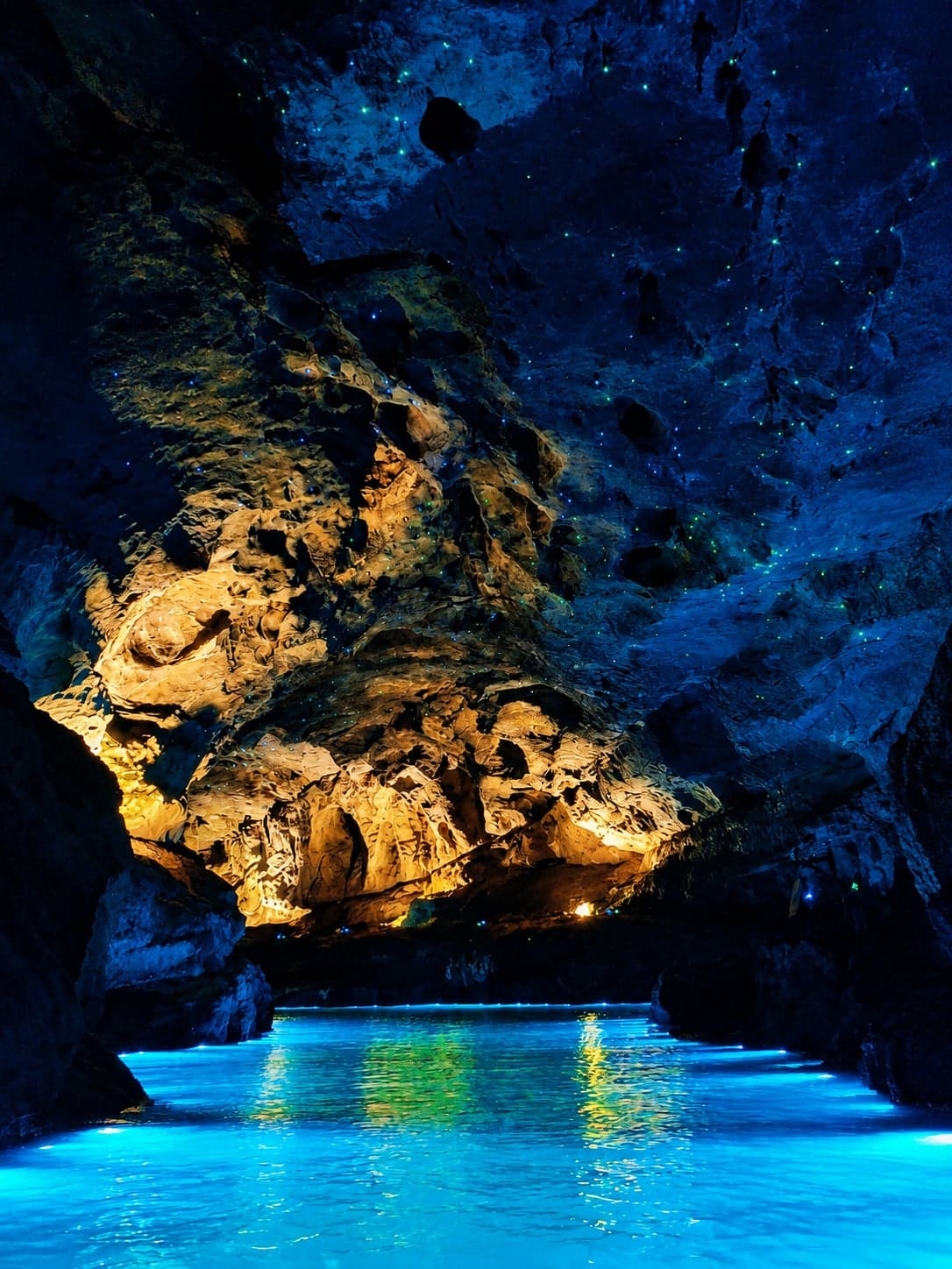 Dinghai Shenzhen, the Sea-Calming Needle stalagmite inside Huanglong Cave east of Zhangjiajie, lit pathways winding past the underground river of the karst system