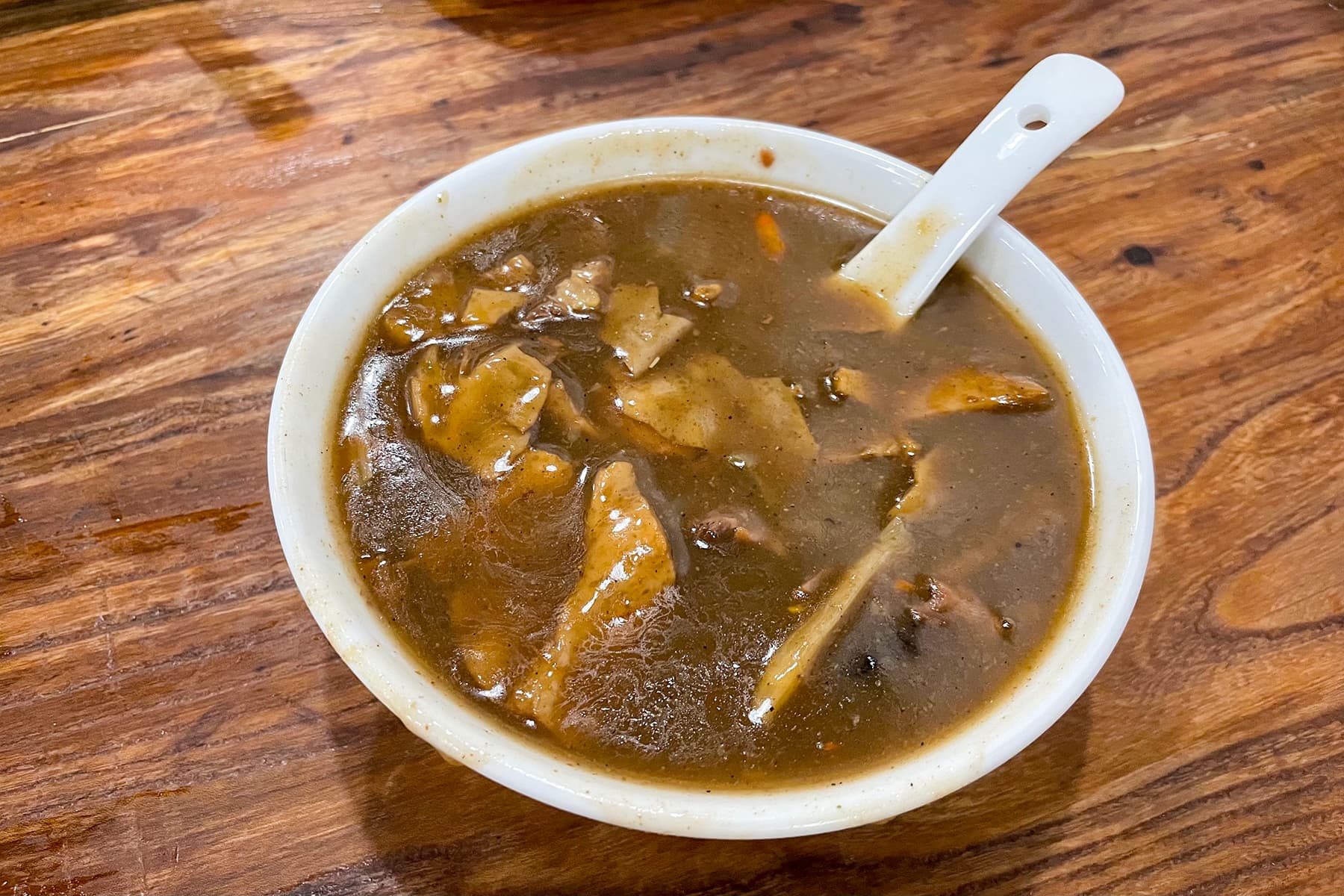 A bowl of Henan Hu La Tang pepper soup with beef strips, daylily, wood ear and vermicelli, mantou bread on a side plate, Zhengzhou